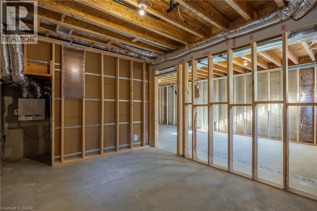 Unfinished basement featuring exposed wood joists, concrete flooring, stud framing, visible ductwork, and electrical conduit - 107 Amber Street, Waterford, ON - Indoor Photo Showing Basement