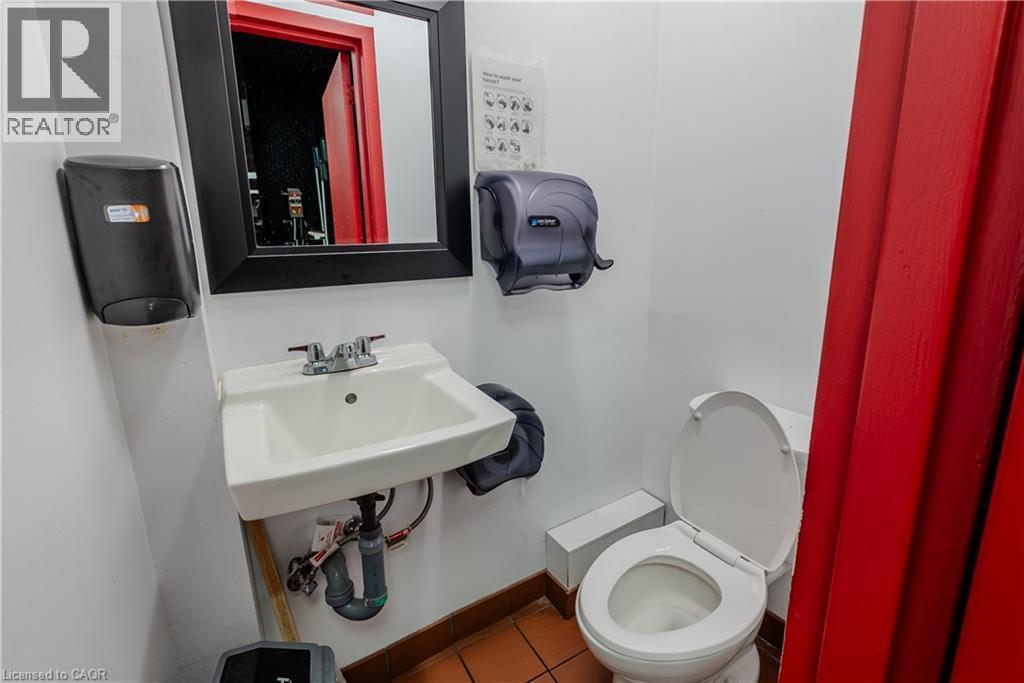 Restroom featuring a wall-mounted sink, chrome faucet, white toilet, and terra cotta tile flooring - 96 Gerrard St E, Toronto, ON