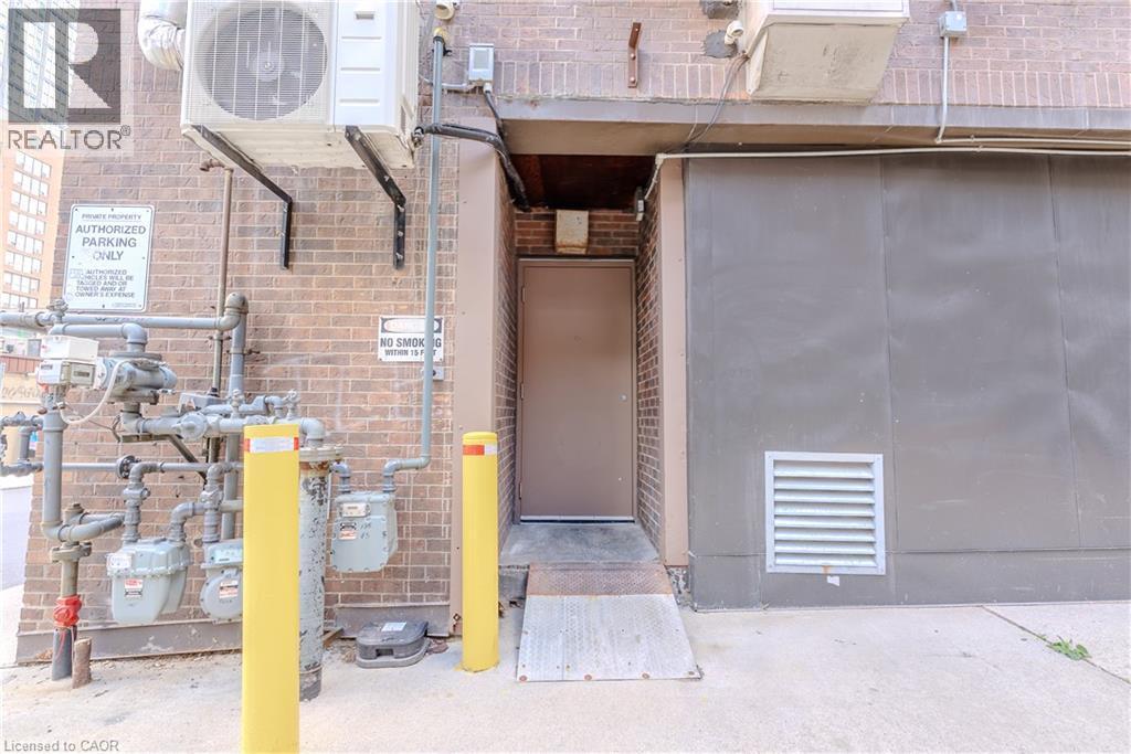 Brick exterior featuring a utility door with an access ramp, adjacent to a large gray panel - 96 Gerrard St E, Toronto, ON
