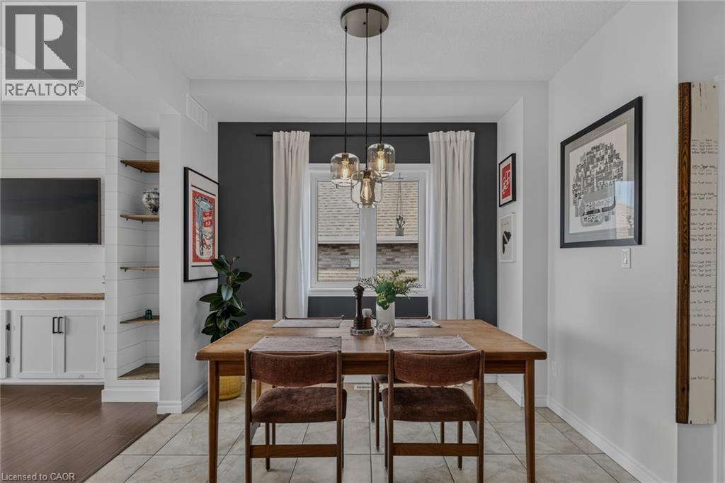 Dining area featuring a contemporary pendant light fixture, a window with drapery, and tile flooring - 174 Woodway Trail, Simcoe, ON - Indoor Photo Showing Dining Room