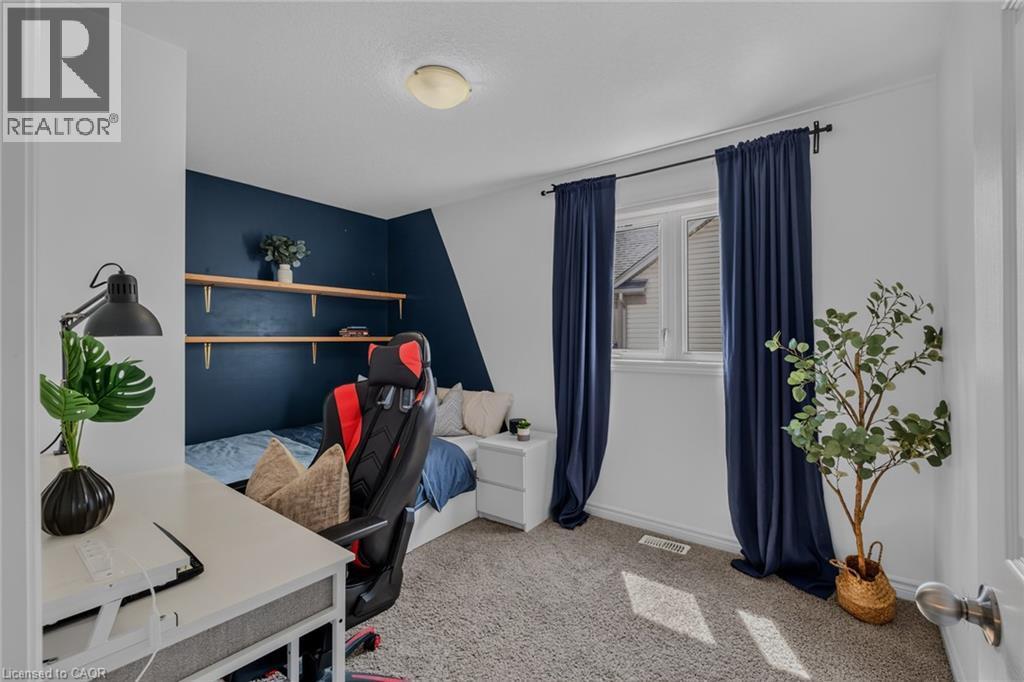 Carpeted room featuring a window with dark drapery, a partial accent wall, and built-in wall shelving - 174 Woodway Trail, Simcoe, ON - Indoor