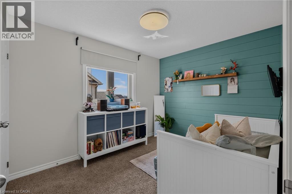 Room featuring a shiplap accent wall, neutral carpeting, and a window with a roller shade - 174 Woodway Trail, Simcoe, ON - Indoor