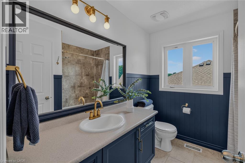 Contemporary bathroom featuring a vanity with a light-colored countertop, an undermount sink, and brass fixtures - 174 Woodway Trail, Simcoe, ON - Indoor Photo Showing Bathroom