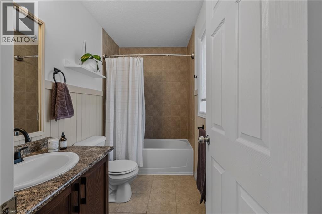 Bathroom featuring a white bathtub, ceramic tile shower surround, and a vanity with a white basin and patterned countertop - 174 Woodway Trail, Simcoe, ON - Indoor Photo Showing Bathroom
