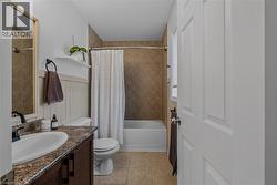 Bathroom featuring a white bathtub, ceramic tile shower surround, and a vanity with a white basin and patterned countertop -