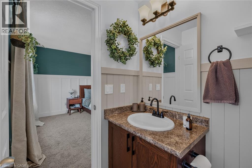 Bathroom vanity featuring a brown wood-finish cabinet with a white oval sink and dark countertop - 174 Woodway Trail, Simcoe, ON - Indoor Photo Showing Bathroom