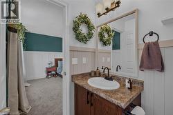 Bathroom vanity featuring a brown wood-finish cabinet with a white oval sink and dark countertop -