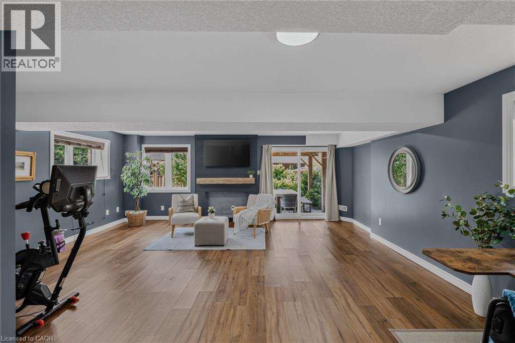 Spacious living area featuring wood-finish flooring, recessed lighting, and a fireplace with a substantial wood mantel - 174 Woodway Trail, Simcoe, ON - Indoor Photo Showing Living Room With Fireplace
