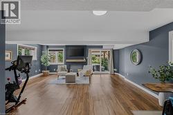 Spacious living area featuring wood-finish flooring, recessed lighting, and a fireplace with a substantial wood mantel -