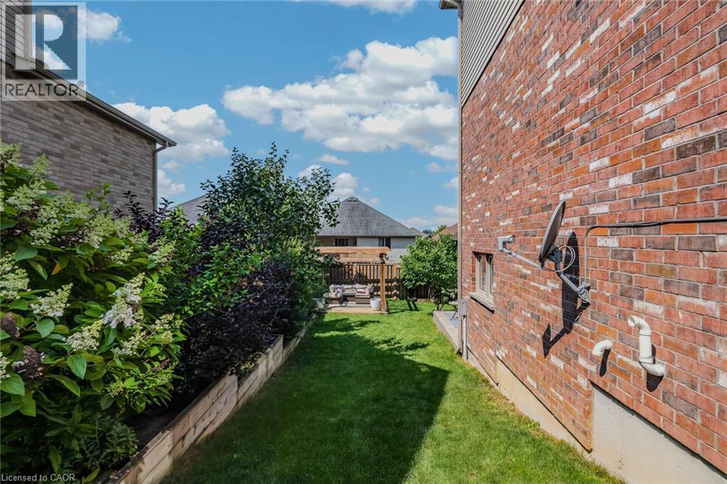 Manicured lawn area with a wooden retaining wall and established plantings - 174 Woodway Trail, Simcoe, ON - Outdoor