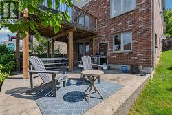 Lower-level patio featuring stamped concrete, a grassed area, and a covered wooden deck structure -