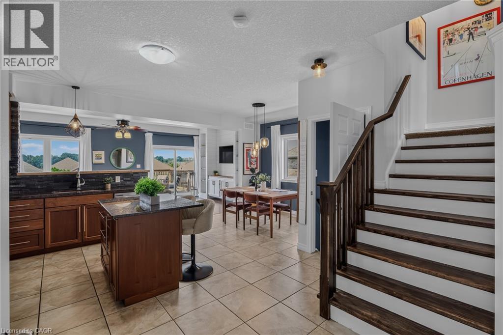 Open-concept kitchen and dining area featuring tile flooring, dark wood cabinetry, and a central island with a granite-style countertop - 174 Woodway Trail, Simcoe, ON - Indoor Photo Showing Other Room
