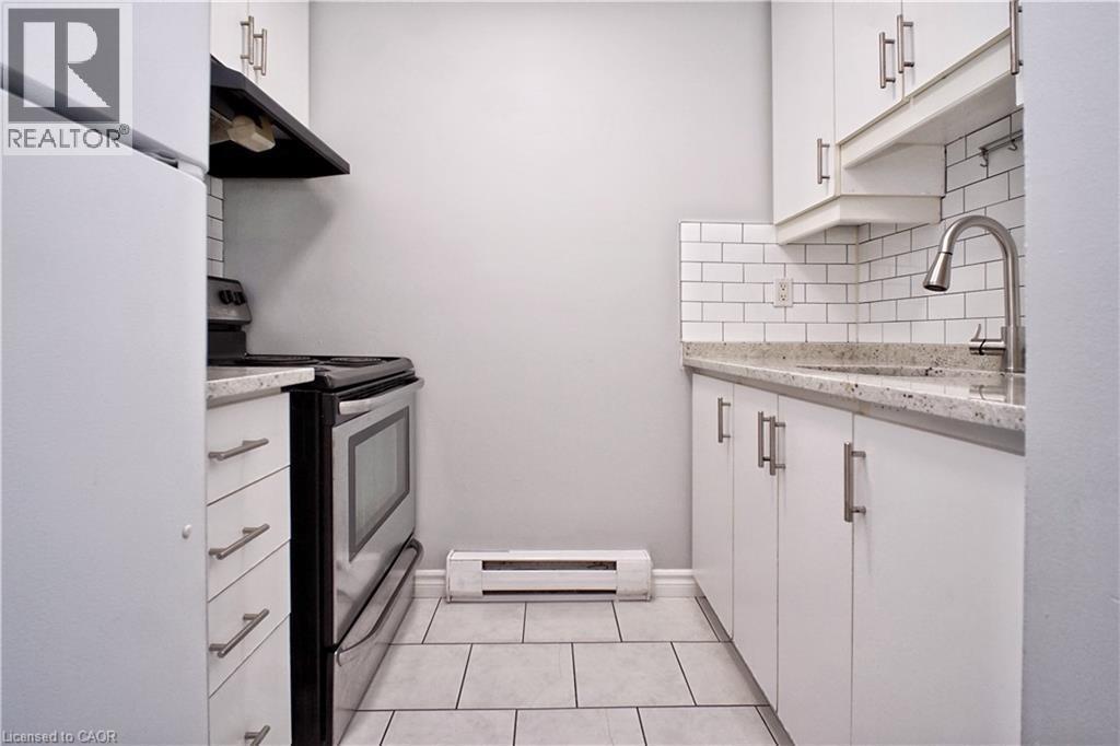 Kitchen featuring white cabinetry with brushed nickel hardware, speckled countertops, subway tile backsplash, and stainless steel appliances - 119 Cedar Street S Unit# 14, Kitchener, ON - Indoor Photo Showing Kitchen