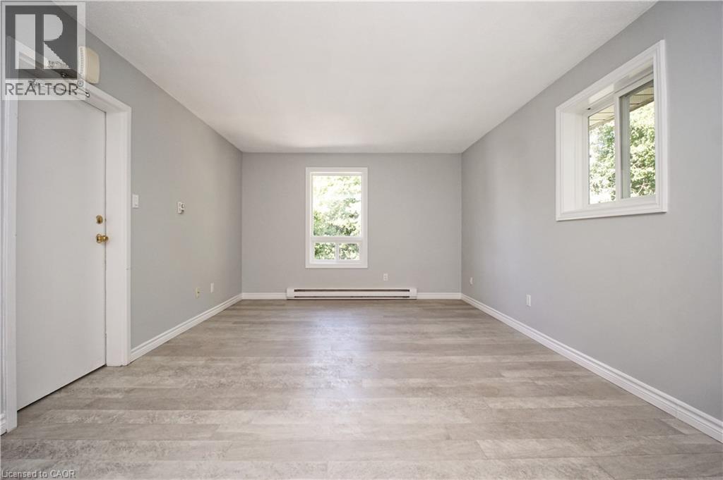Spacious room featuring light grey walls, wood-finish flooring, white trim, and two windows providing natural light - 119 Cedar Street S Unit# 14, Kitchener, ON - Indoor Photo Showing Other Room