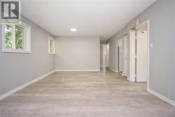 Spacious room featuring light wood-finish flooring, two windows with white trim, and a ceiling-mounted light fixture -