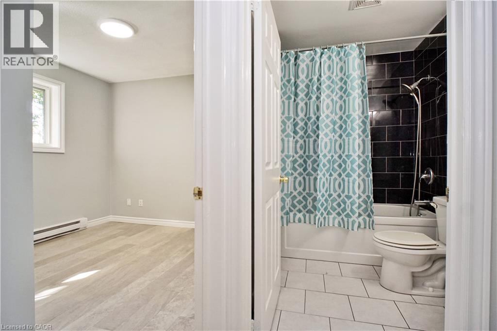 Bathroom featuring a white bathtub, dark subway tile surround, and white floor tiling - 119 Cedar Street S Unit# 14, Kitchener, ON - Indoor Photo Showing Bathroom