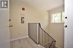 Stairwell with light-toned walls, wood-finish flooring, and black metal railing -