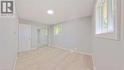 Spacious room featuring wood-finish flooring, light grey walls, and a recessed ceiling light -