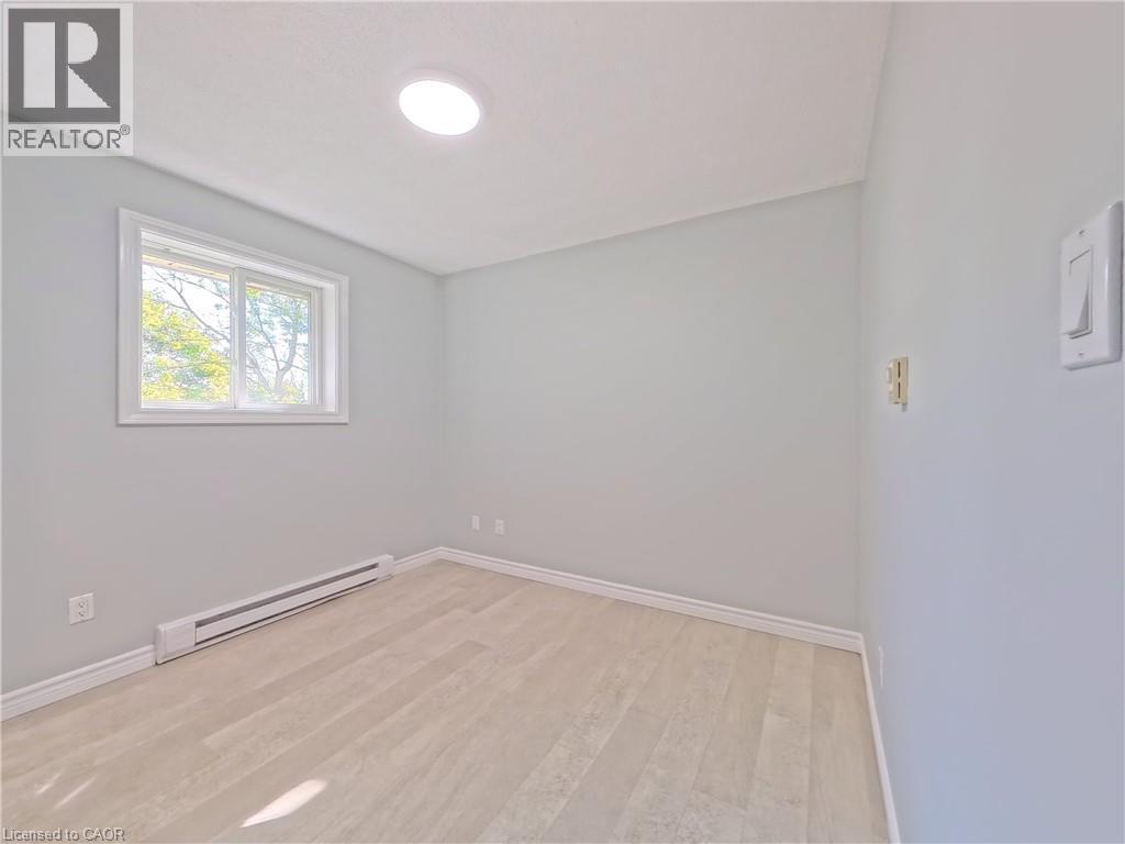 Room featuring light-toned wood-finish flooring, a white trim baseboard, and a round ceiling light fixture - 119 Cedar Street S Unit# 14, Kitchener, ON - Indoor Photo Showing Other Room