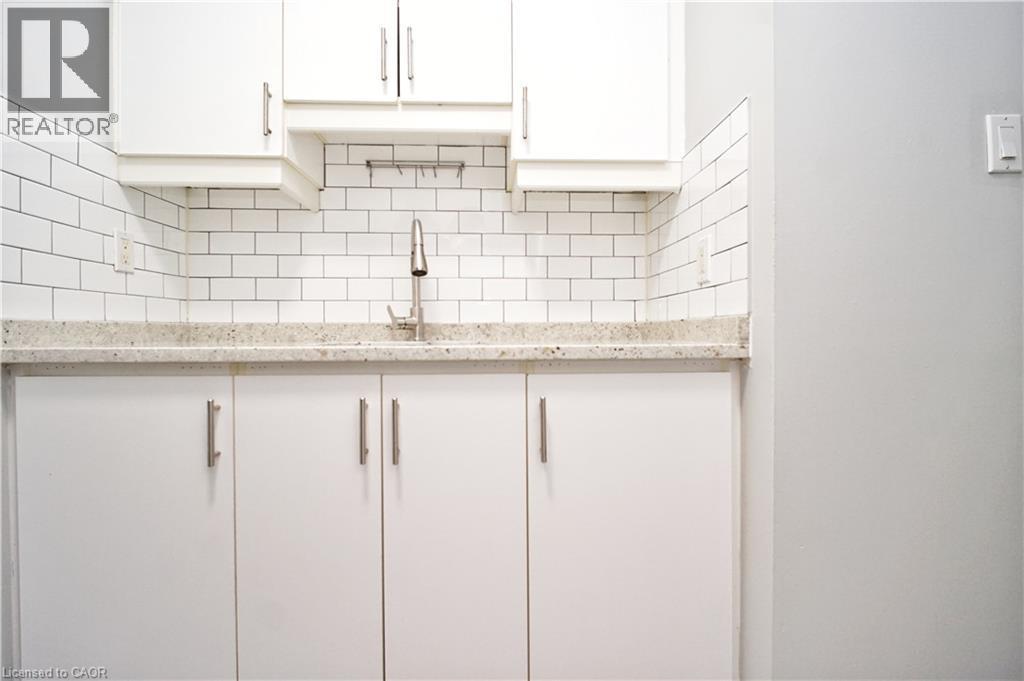 White cabinetry with brushed nickel hardware, light-toned countertop, and classic subway tile backsplash - 119 Cedar Street S Unit# 14, Kitchener, ON - Indoor Photo Showing Kitchen
