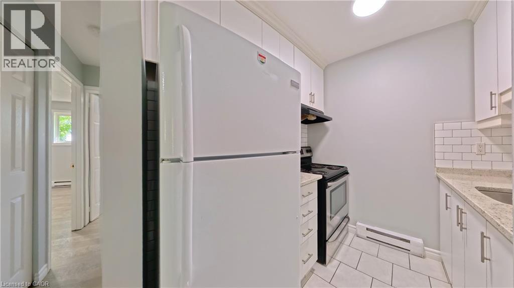 Compact kitchen featuring white cabinetry, a white refrigerator, and a stainless steel oven - 119 Cedar Street S Unit# 14, Kitchener, ON - Indoor Photo Showing Kitchen