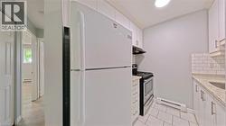 Compact kitchen featuring white cabinetry, a white refrigerator, and a stainless steel oven -