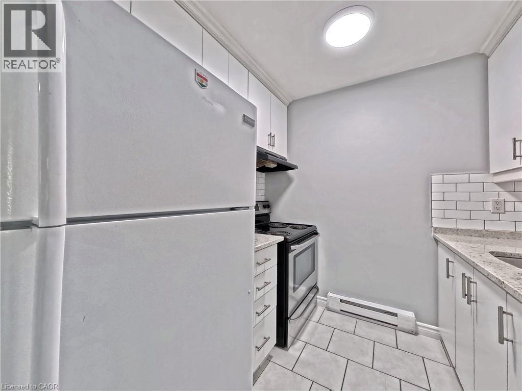 Kitchen featuring white appliances, white subway tile backsplash, white cabinetry with contemporary pulls, granite-style countertops, and a tile floor - 119 Cedar Street S Unit# 14, Kitchener, ON - Indoor Photo Showing Kitchen