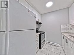 Kitchen featuring white appliances, white subway tile backsplash, white cabinetry with contemporary pulls, granite-style countertops, and a tile floor -