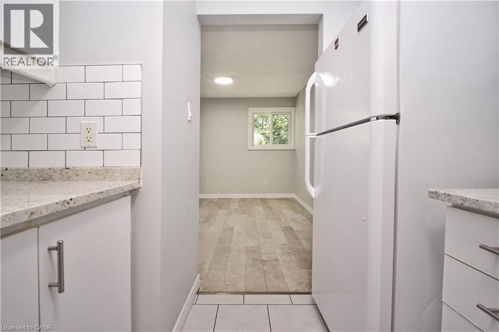 Kitchen area featuring white cabinetry, subway tile backsplash, and light-toned countertop - 119 Cedar Street S Unit# 14, Kitchener, ON - Indoor