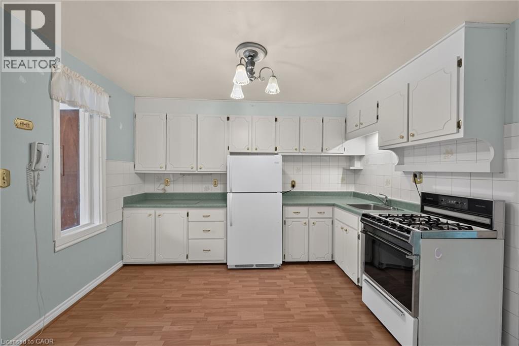 Kitchen featuring white cabinetry, light green countertops, white tile backsplash, and wood-finish flooring - 155 Newlands Avenue, Hamilton, ON - Indoor Photo Showing Kitchen