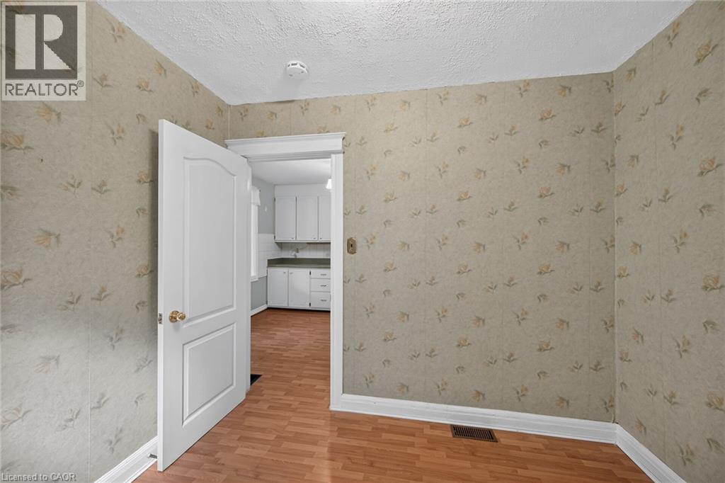 Interior room featuring wood-finish flooring, patterned wallpaper, and white baseboards - 155 Newlands Avenue, Hamilton, ON - Indoor Photo Showing Other Room