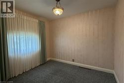 Room featuring textured wallpaper, wall-to-wall carpeting, and a window with both sheer and solid drapes -