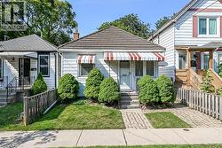 Charming bungalow exterior featuring horizontal siding, a red and white striped awning, and a tiled roof -