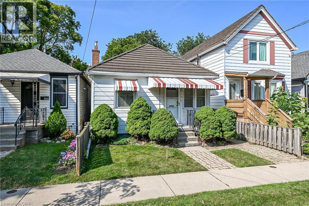 White siding exterior with a shingled roof, featuring a front porch with a striped awning - 155 Newlands Avenue, Hamilton, ON - Outdoor