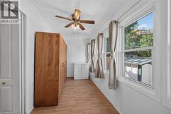 Interior room featuring wood-finish flooring, white walls, and a ceiling fan with light fixture -