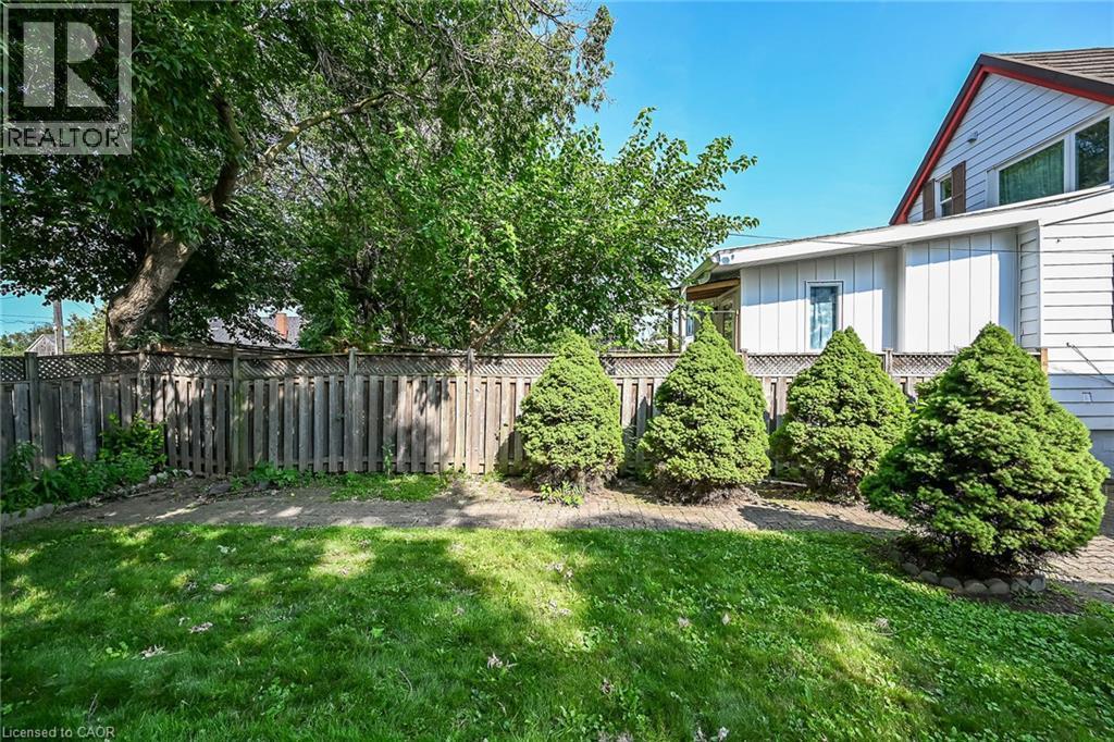 Expansive backyard featuring a lush lawn, mature trees, and a wooden privacy fence with lattice detailing - 155 Newlands Avenue, Hamilton, ON - Outdoor