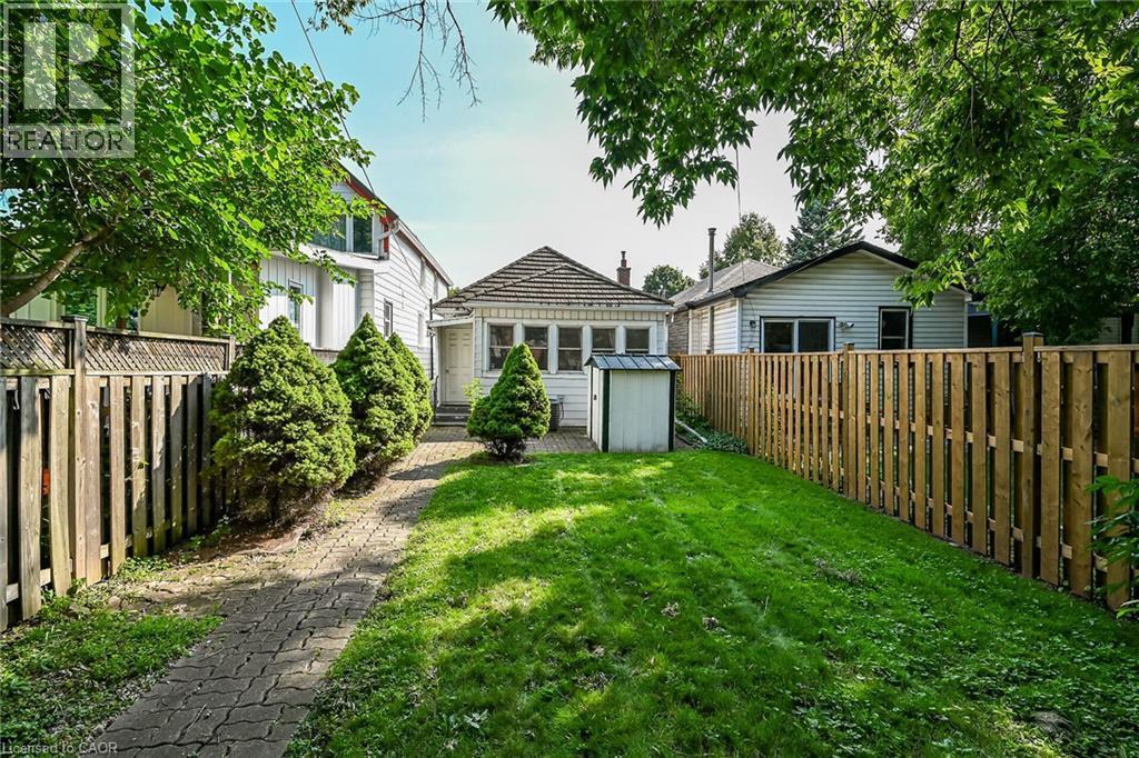 Expansive backyard featuring a manicured lawn, paved pathway, and privacy fencing - 155 Newlands Avenue, Hamilton, ON - Outdoor
