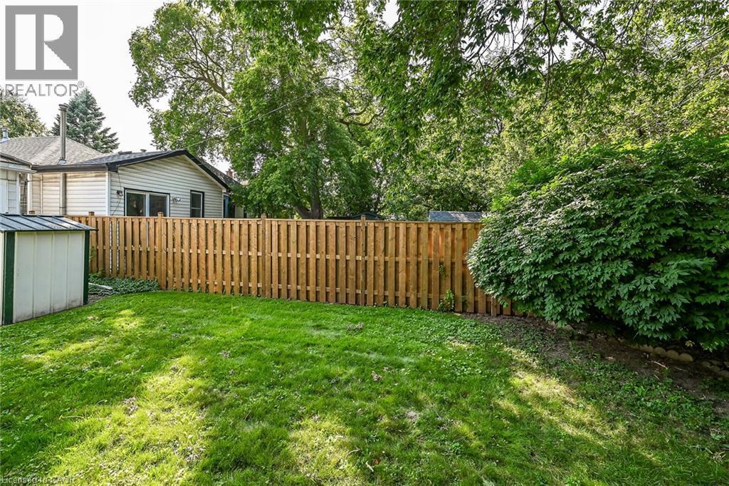 Spacious backyard featuring a manicured lawn, a full wood privacy fence, mature trees, and established perimeter landscaping - 155 Newlands Avenue, Hamilton, ON - Outdoor