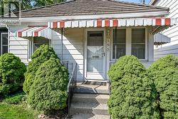 White siding exterior featuring a red and white striped awning over the front entry -