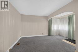 Room featuring light-toned striped wallpaper, gray carpeting, and white baseboards -