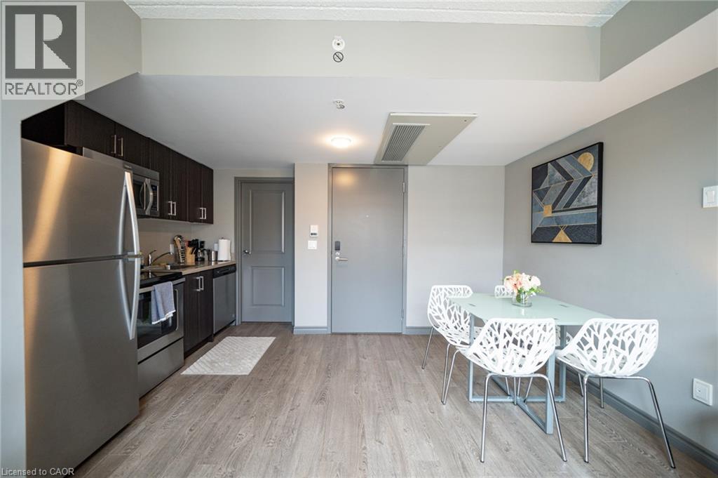 Modern kitchen featuring stainless steel appliances, dark wood-finish cabinetry, and wood-finish flooring - 321 Spruce Street Unit# 710, Waterloo, ON - Indoor