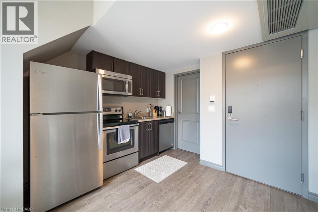 Compact kitchen featuring stainless steel appliances, including a refrigerator, range, microwave, and dishwasher - 321 Spruce Street Unit# 710, Waterloo, ON - Indoor Photo Showing Kitchen With Stainless Steel Kitchen