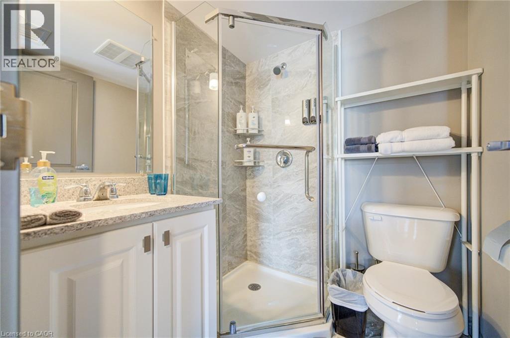 Bathroom featuring a walk-in shower with glass enclosure, white vanity with stone-finish countertop, and a built-in mirror - 321 Spruce Street Unit# 710, Waterloo, ON - Indoor Photo Showing Bathroom