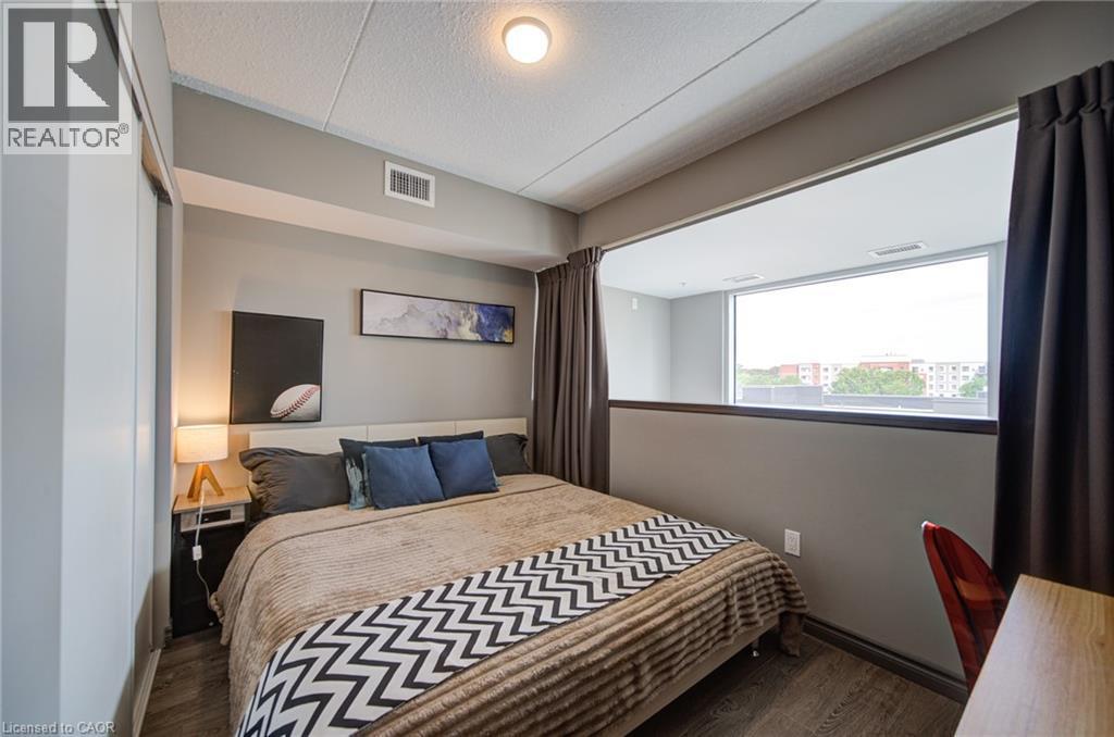 Well-lit sleeping area featuring a built-in window opening, wood-finish flooring, and a flush-mount ceiling light - 321 Spruce Street Unit# 710, Waterloo, ON - Indoor Photo Showing Bedroom