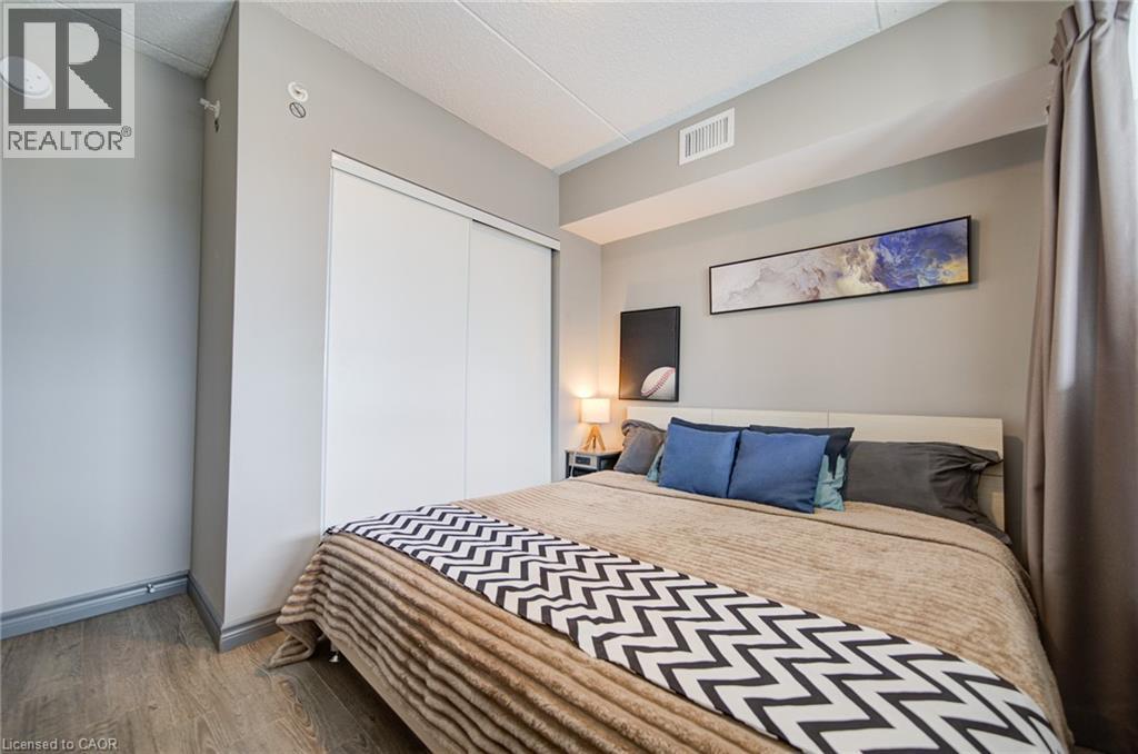 Bedroom featuring wood-finish flooring, a neutral color palette, built-in sliding closet doors, and recessed lighting - 321 Spruce Street Unit# 710, Waterloo, ON - Indoor Photo Showing Bedroom