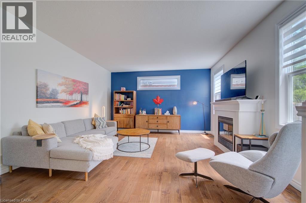 Bright living area featuring wood-finish flooring, a prominent white mantelpiece with an integrated fireplace, and windows with horizontal blinds - 729 Keats Way, Waterloo, ON - Indoor Photo Showing Living Room With Fireplace