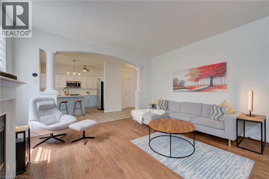 Open-concept living space featuring wood-finish flooring, white walls, an arched entryway, and a fireplace mantel - 729 Keats Way, Waterloo, ON - Indoor Photo Showing Living Room