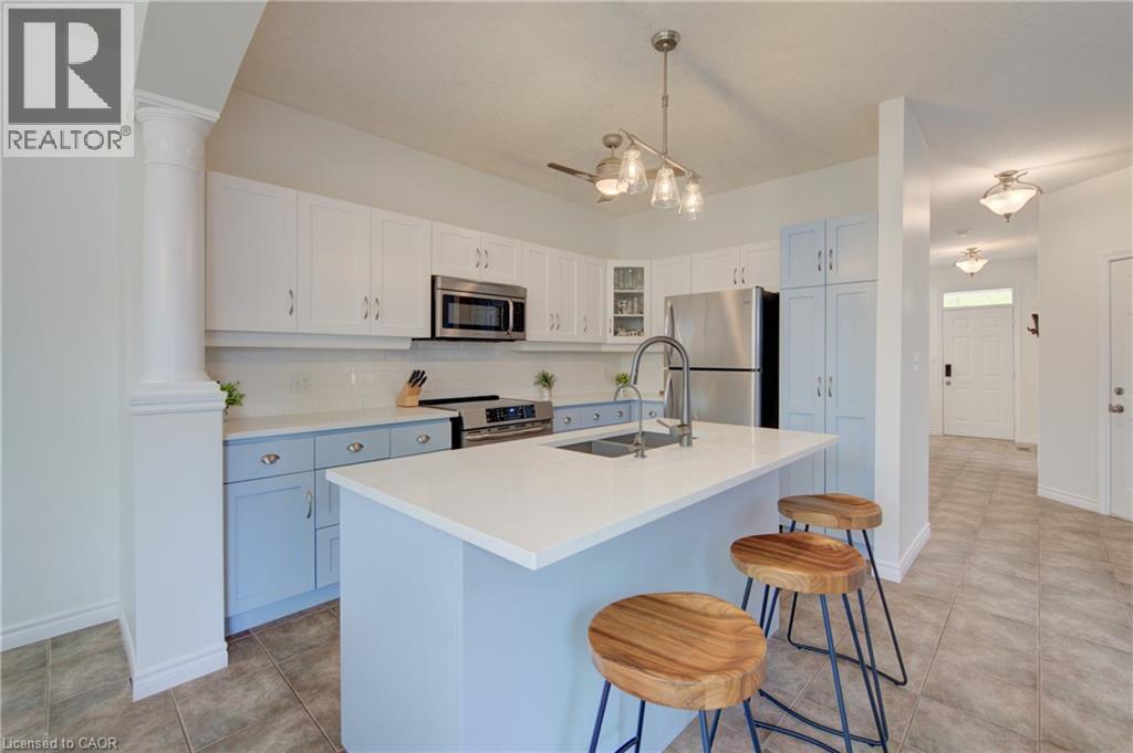 Kitchen featuring a central island with a solid surface countertop, stainless steel appliances, two-tone cabinetry, and a subway tile backsplash - 729 Keats Way, Waterloo, ON - Indoor Photo Showing Kitchen With Double Sink