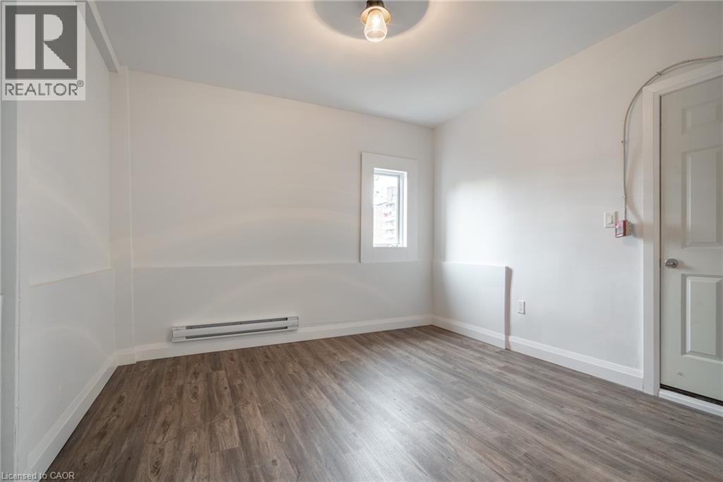 Room with wood-finish flooring, white walls, and a single window - 524 King Street E Unit# 3, Hamilton, ON - Indoor Photo Showing Other Room