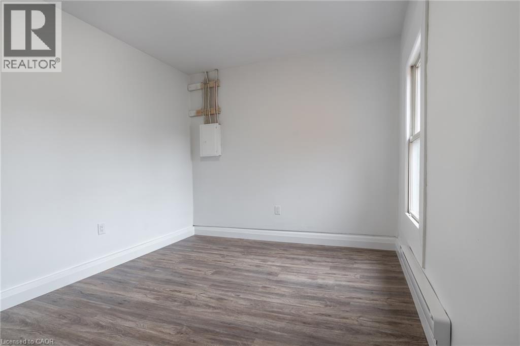 Versatile room featuring wood-finish flooring, crisp white walls, and a large window providing natural illumination - 524 King Street E Unit# 3, Hamilton, ON - Indoor Photo Showing Other Room